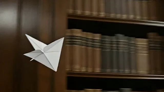 Video frame extractor output: frame 20 of a paper airplane flying through a library